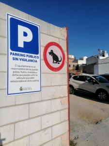 un cartel en una pared de ladrillo con un estacionamiento con un cartel de cerdo en Hospedium Hostal Temático Desde La Judería en Arjona