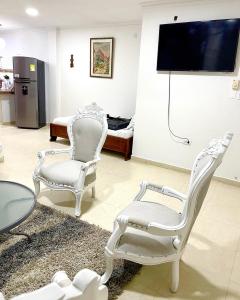 a living room with two white chairs and a tv at Casa Dimares in Cartagena de Indias