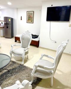 uma sala de estar com duas cadeiras brancas e uma televisão em Casa Dimares em Cartagena das Índias