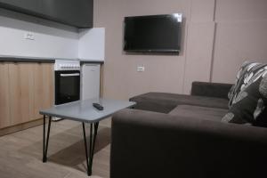 a living room with a couch and a table and a tv at Villa FAMILY in Kumanovo