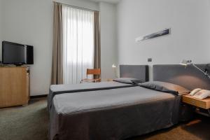 a hotel room with two beds and a television at Albergo Alla Posta in Trieste