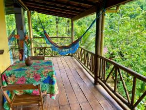 a porch with a table and a hammock on it at Casa Tambor Paraty in Paraty