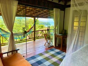 a bedroom with a balcony with a view of the ocean at Casa Tambor Paraty in Paraty