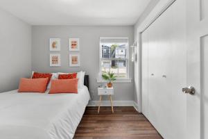 1 dormitorio con cama blanca y almohadas de color naranja en Charming Modern 3-Bedroom Home in East Nashville! en Nashville