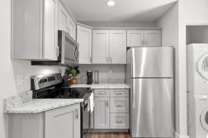 cocina con armarios blancos y nevera de acero inoxidable en Charming Modern 3-Bedroom Home in East Nashville! en Nashville