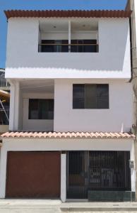 a white house with a brown garage at Hospedaje Petro Talara in Talara