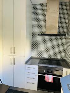 - une cuisine avec des placards blancs et une cuisinière noire dans l'établissement Lovely Apartment to feel Lisbon, à Lisbonne