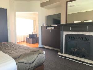 a bedroom with a fireplace and a bed at Blazing Stump Motel & Suites in Wodonga