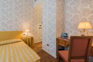 a bedroom with a bed and a desk and a chair at Albergo Alla Posta in Trieste