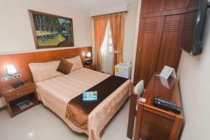 - une chambre avec un lit, un bureau et une télévision dans l'établissement HOTEL ACHALAY, à Popayan