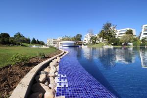 una piscina con azulejos azules en el agua en Alvor Vila Marachique Apartment, en Alvor