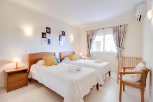 1 dormitorio con 2 camas, silla y ventana en Alvor Vila Marachique Apartment, en Alvor