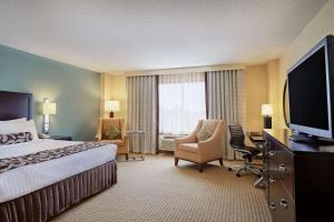 a hotel room with a bed, chair and television at Sonesta Atlanta Airport North in Atlanta