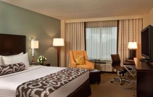 a hotel room with a bed and a desk and chair at Sonesta Atlanta Airport North in Atlanta