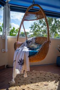 a wicker swing chair on a porch with a blanket at Pina Mimosa - Airlie Beach in Airlie Beach