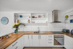 a kitchen with white cabinets and wooden counter tops at Pina Mimosa - Airlie Beach in Airlie Beach