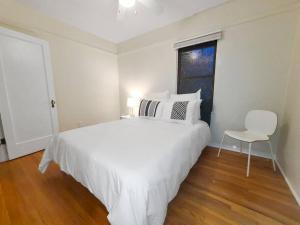 ein weißes Schlafzimmer mit einem weißen Bett und einem Stuhl in der Unterkunft North Park Bungalow Resort in San Diego