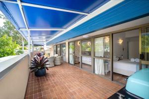 an outdoor deck with a blue roof and a patio at Pina Mimosa - Airlie Beach in Airlie Beach