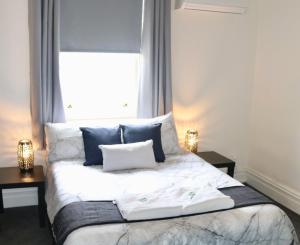 Un dormitorio con una cama con almohadas azules y una ventana en The Commercial Hotel Wallerawang, en Wallerawang