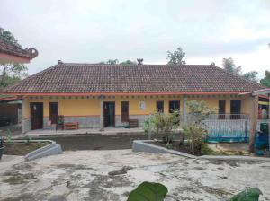 uma casa amarela com telhado de azulejo em Penginapan Mentorogo Kaliurang Mitra RedDoorz em Kaliurang