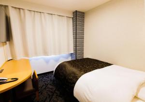 a hotel room with a bed and a desk and a window at APA Hotel Kokuraeki Shinkansenguchi in Kitakyushu