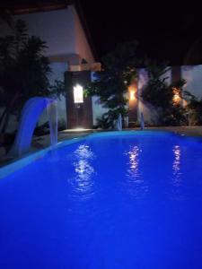 Casa em Mundaú Trairi-Ce في ترايري: حمام سباحة في الليل مع أضواء زرقاء