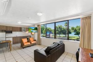 a living room with a couch and a kitchen at Waters Edge The Strand in Townsville