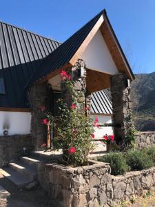 a stone building with red flowers in front of it at Casa El Ciprés in Potrerillos