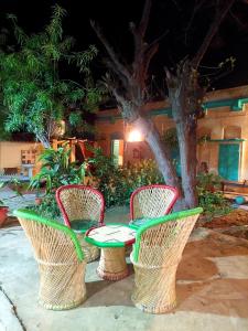 three chairs and a table in front of a building at Virasat E Punjab -Farmstay Amritsar in Nūruddīn