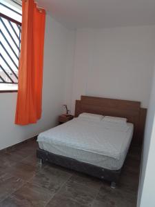 - une chambre avec un lit et un rideau orange dans l'établissement Habitaciones Don Pelu, à Máncora