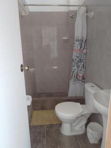 La salle de bains est pourvue de toilettes et d'un rideau de douche. dans l'établissement Habitaciones Don Pelu, à Máncora