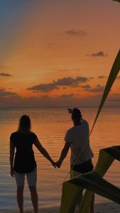 Un uomo e una donna in piedi sulla spiaggia al tramonto di Olive Goidhoo a Fehendhoo