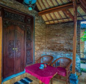 una mesa con 2 sillas y una puerta de madera en Kajeng Bungalow, en Ubud