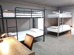 2 literas en una habitación con mesa y mesa gmaxwell gmaxwell gmaxwell gmaxwell en HIT Hostel, en Auckland