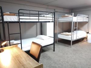 two bunk beds in a room with a table and a table gmaxwell gmaxwell gmaxwell gmaxwell at HIT Hostel in Auckland