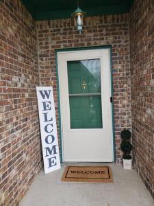 uma porta branca com um sinal de boas-vindas ao lado de uma parede de tijolos em Cozy Indy Home em Indianápolis