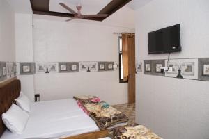 a bedroom with a bed and a flat screen tv at Hotel Al Sharif Manzil 90 Mtrs from Dargah in Ajmer