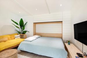 - une chambre avec un lit et un canapé jaune dans l'établissement The Other Place Cottage C, à Folly Beach