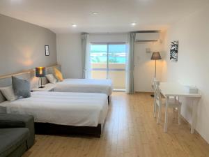 宮古島にあるホテル宮古島のベッド2台とテーブルとソファがあるホテルの部屋