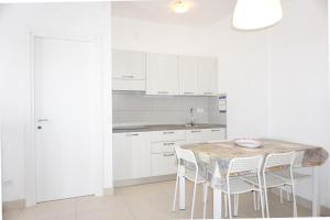 una cucina bianca con tavolo e sedie di Relax by the garden - flat for up to 6 guests a Porto Santa Margherita di Caorle