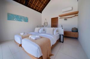 two beds in a bedroom with white walls at Luxury Ocean View Villas with Private Cook and Free Gym Membership in Kuta Lombok +63 photos