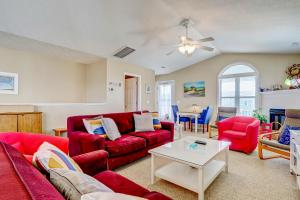 a living room with red couches and a table at Happy Together in Holden Beach