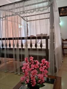 a vase with pink flowers on a table in front of a window at Hotel Dolphin Hikkaduwa in Hikkaduwa