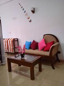 a living room with a couch with colorful pillows at Hotel Dolphin Hikkaduwa in Hikkaduwa