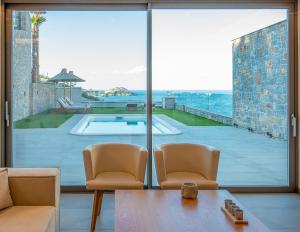 a living room with a view of a swimming pool through a window at Ligaria Mare in Agia Pelagia