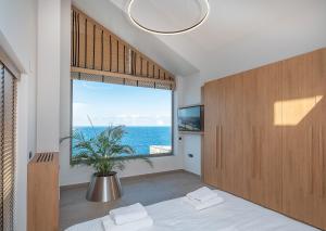 a bedroom with a large window with the ocean at Ligaria Mare in Agia Pelagia