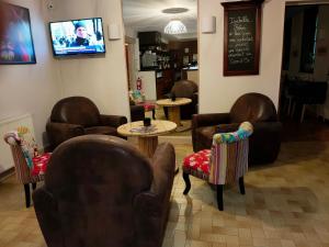 a waiting room with leather chairs and tables and a tv at Au Lion d'or in Saint-Pol-sur-Ternoise