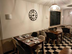 Au Lion d'or في Saint-Pol-sur-Ternoise: غرفة طعام مع طاولات وكراسي وساعة على الحائط