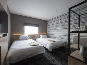a bedroom with two beds and a window at Tmark City Hotel Kanazawa in Kanazawa