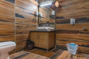 a bathroom with wooden walls and a toilet and a sink at The Hillcrest Paradise in Kasauli